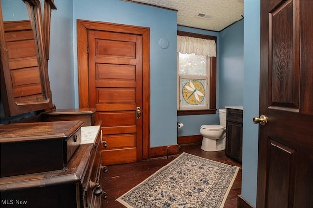 bathroom featuring baseboards, toilet, wood finished floors, and visible vents