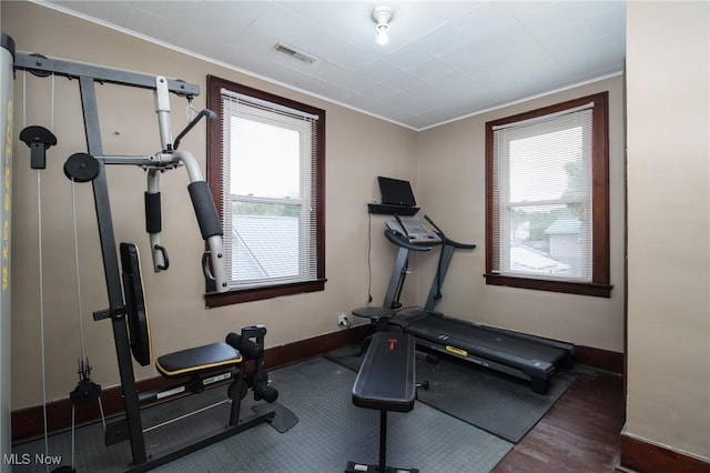 workout room with baseboards, visible vents, ornamental molding, and wood finished floors