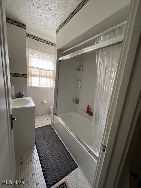 full bathroom featuring tile patterned flooring, vanity, toilet, a textured ceiling, and shower / bath combination with curtain