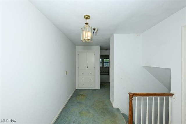 corridor featuring baseboards and carpet