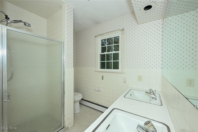 bathroom featuring a sink, tile walls, a shower stall, baseboard heating, and wallpapered walls