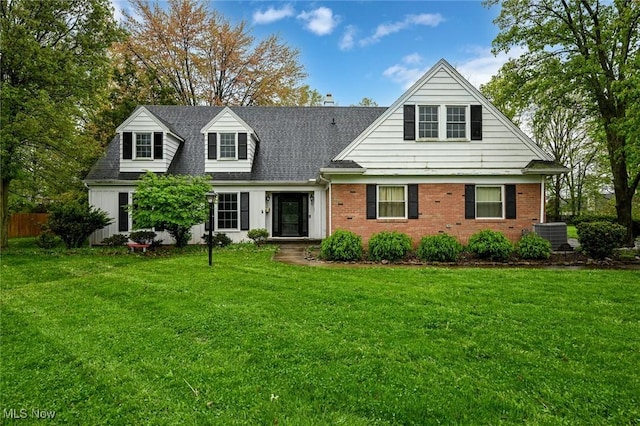 cape cod-style house with cooling unit, fence, a front yard, brick siding, and roof with shingles