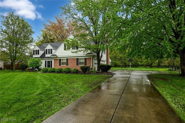 view of front facade with concrete driveway, a front yard, and brick siding
