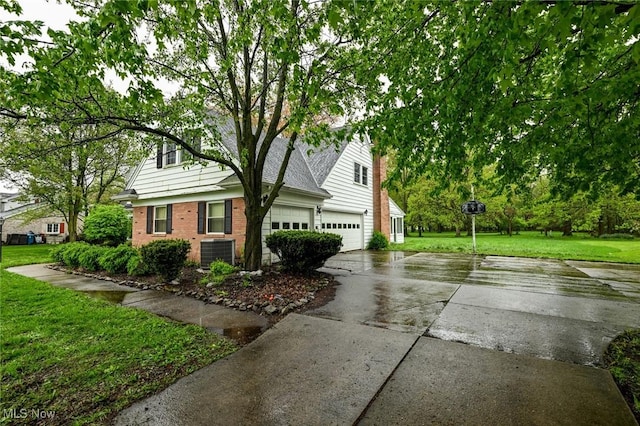 view of property exterior featuring concrete driveway, a yard, brick siding, and central air condition unit