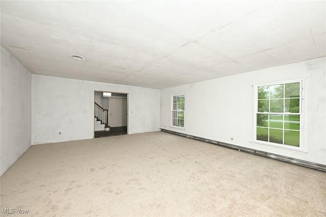 unfurnished room featuring stairs, carpet, and a healthy amount of sunlight