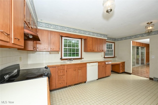 kitchen with white dishwasher, under cabinet range hood, a sink, backsplash, and light countertops