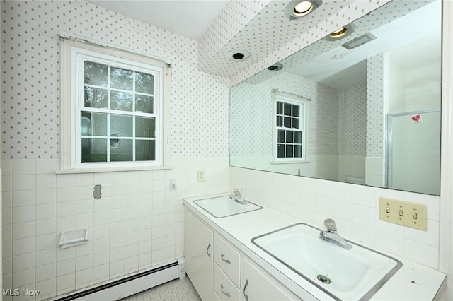 bathroom featuring tile walls, baseboard heating, wallpapered walls, and a sink
