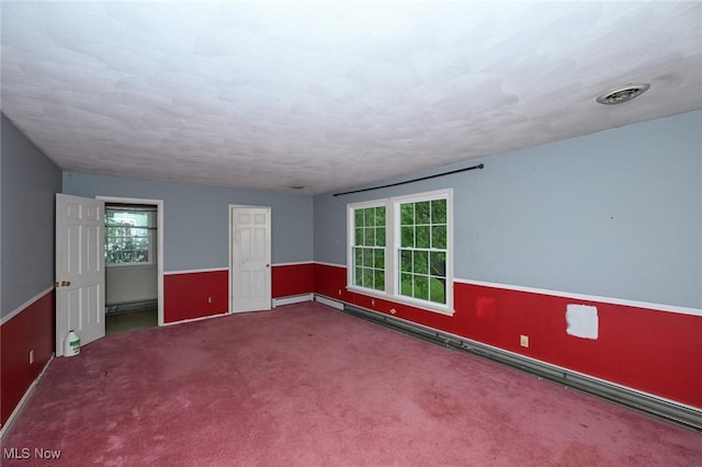empty room featuring carpet flooring, baseboard heating, and visible vents