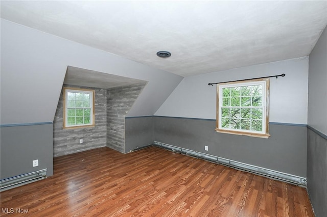 bonus room featuring vaulted ceiling, plenty of natural light, and wood finished floors