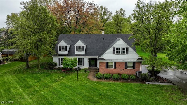 cape cod-style house featuring cooling unit, brick siding, and a front yard