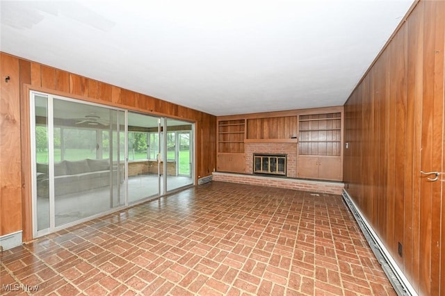 unfurnished living room featuring wood walls, brick floor, and baseboard heating