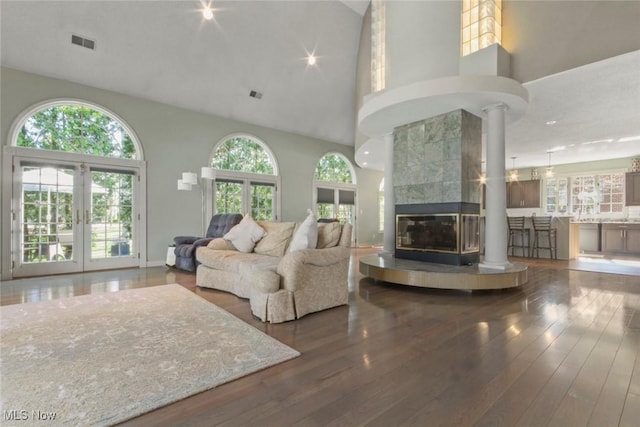 living room with high vaulted ceiling, a healthy amount of sunlight, and visible vents