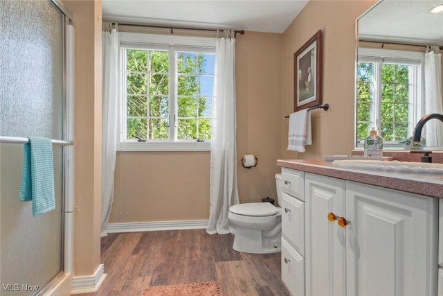 full bathroom with a shower with door, wood finished floors, and a healthy amount of sunlight