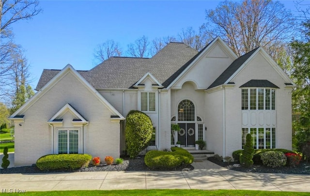 view of front of home featuring a shingled roof and brick siding