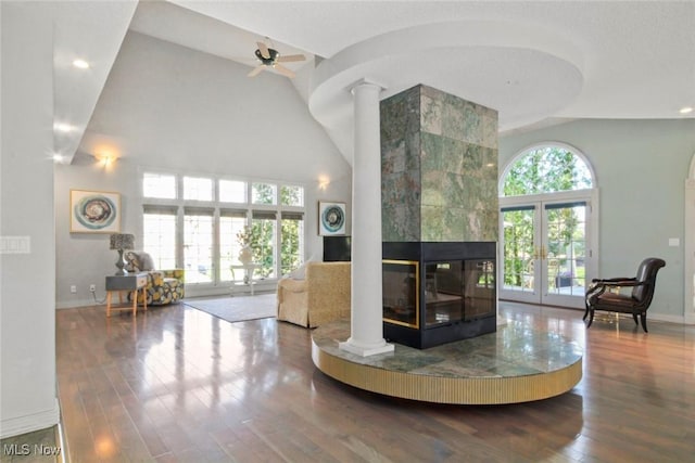 living area featuring baseboards, high vaulted ceiling, decorative columns, and hardwood / wood-style flooring