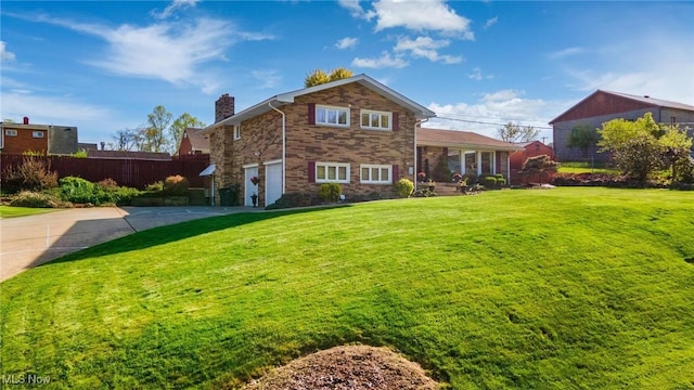 rear view of property featuring an attached garage, fence, a chimney, a lawn, and driveway