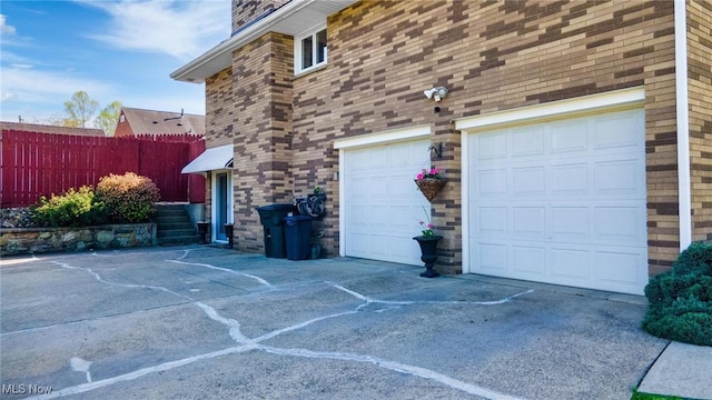 view of side of home with concrete driveway, a chimney, and fence
