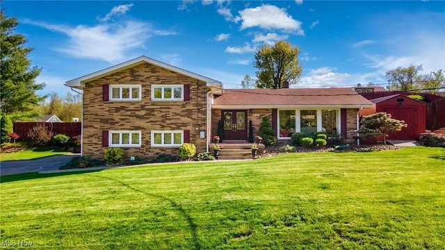 tri-level home with an outbuilding, fence, a front yard, and a storage unit
