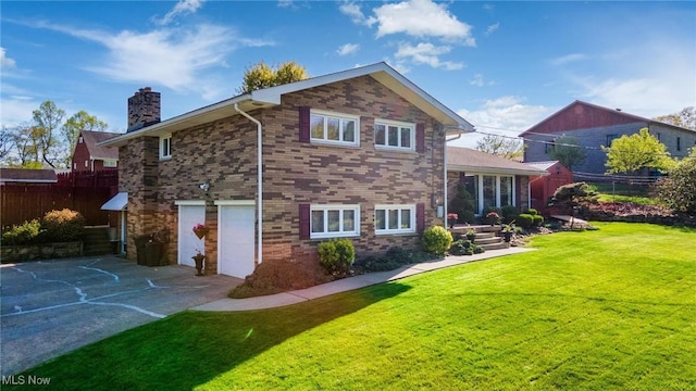 back of property featuring a chimney, a lawn, fence, a garage, and concrete driveway