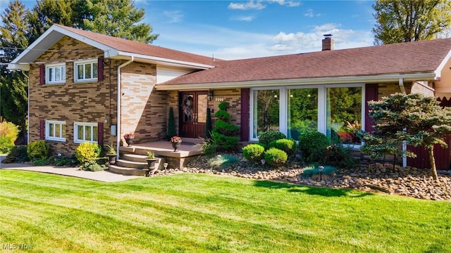 tri-level home with a front lawn, a chimney, and brick siding