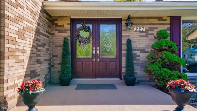 property entrance featuring french doors, brick siding, and covered porch