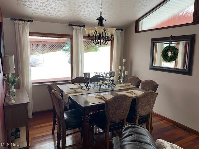 dining area with a textured ceiling, a chandelier, plenty of natural light, and wood finished floors