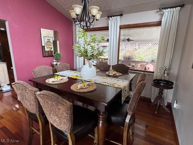 dining room with a chandelier, lofted ceiling, baseboards, and wood finished floors