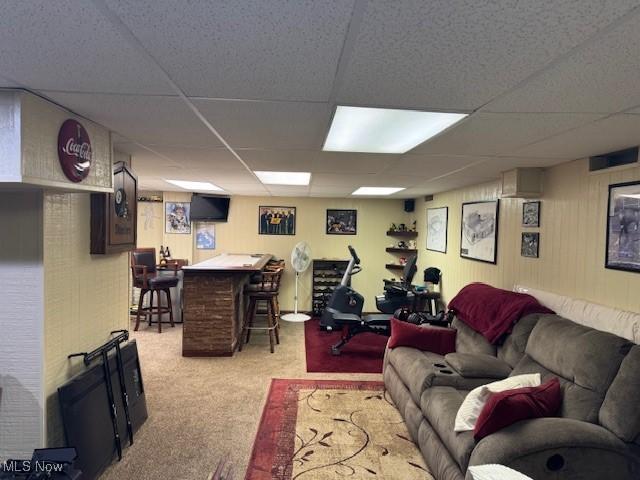 carpeted living room featuring bar area and a paneled ceiling