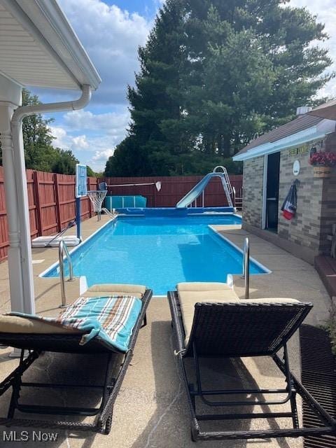 view of pool with a patio, a water slide, a fenced in pool, and a fenced backyard