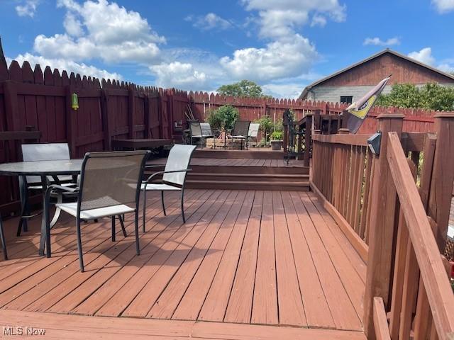 wooden terrace featuring outdoor dining area and a fenced backyard