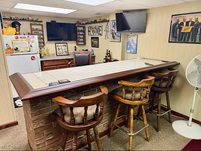 bar featuring freestanding refrigerator, carpet, baseboards, and a paneled ceiling