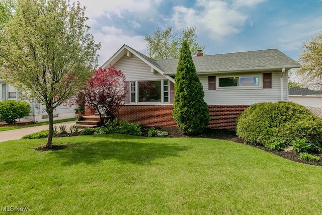 ranch-style home with brick siding, a chimney, and a front yard