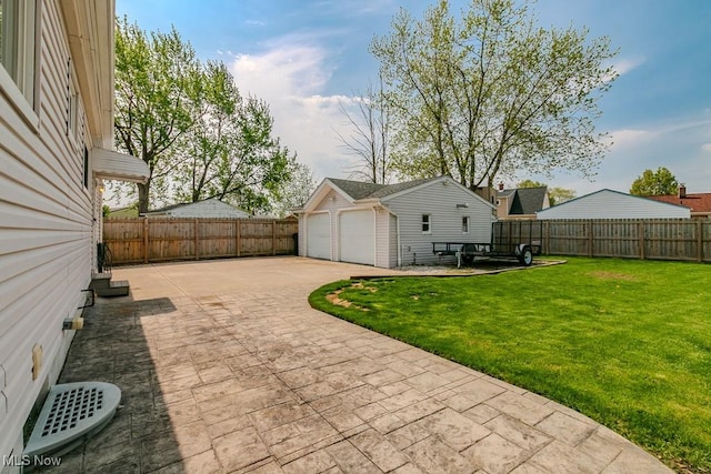 view of yard with a fenced backyard, a detached garage, a patio, and an outbuilding