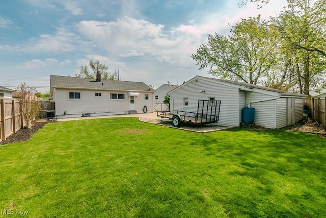 back of property featuring a fenced backyard, a patio area, an outbuilding, and a lawn