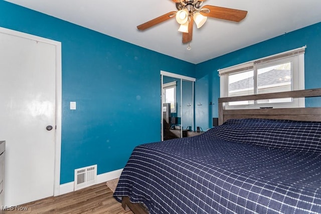 bedroom featuring multiple windows, visible vents, wood finished floors, and a ceiling fan