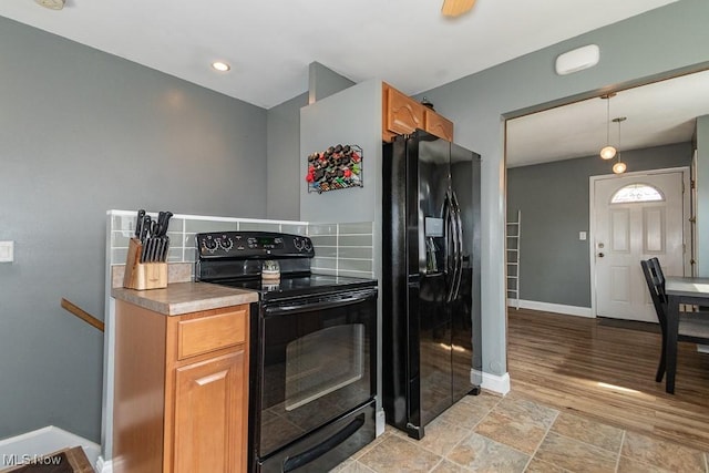kitchen with brown cabinets, baseboards, black appliances, and decorative light fixtures