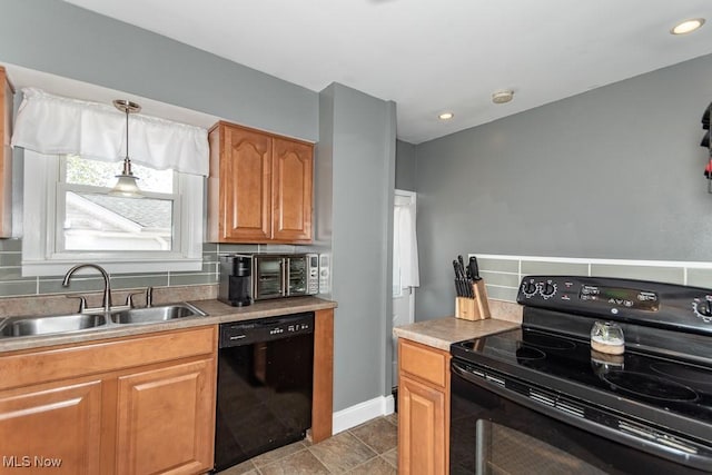 kitchen with a sink, black appliances, light countertops, decorative backsplash, and baseboards