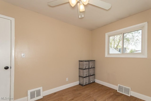empty room with visible vents, wood finished floors, and ceiling fan