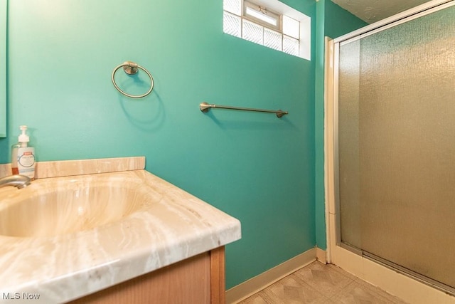 bathroom with a sink, baseboards, and a shower stall