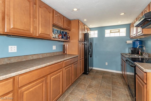 kitchen featuring a sink, brown cabinetry, black appliances, under cabinet range hood, and baseboards
