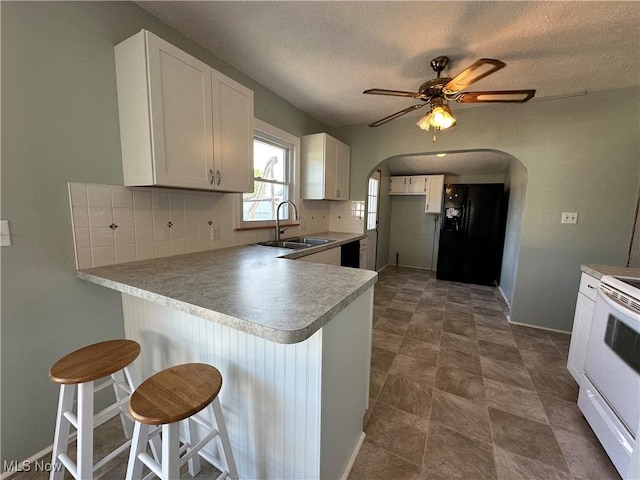 1905 Pine St SE, East Sparta, OH 44626 - kitchen with a sink, a peninsula, black appliances, decorative backsplash, and arched walkways