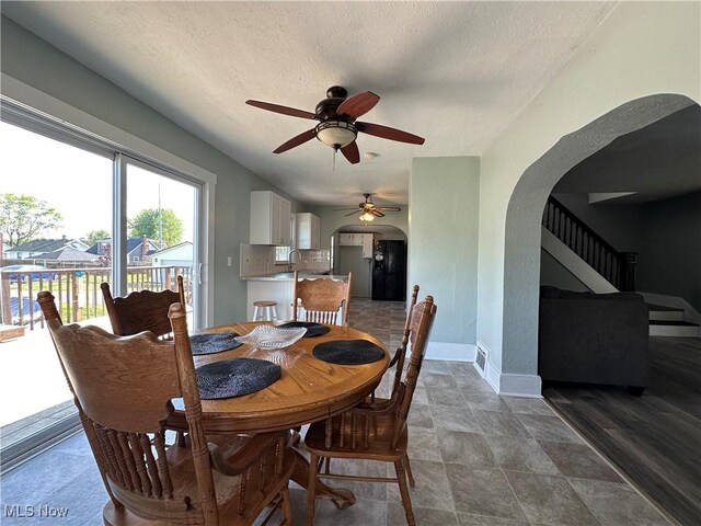 1905 Pine St SE, East Sparta, OH 44626 - dining room featuring a ceiling fan, a textured ceiling, baseboards, arched walkways, and stairway