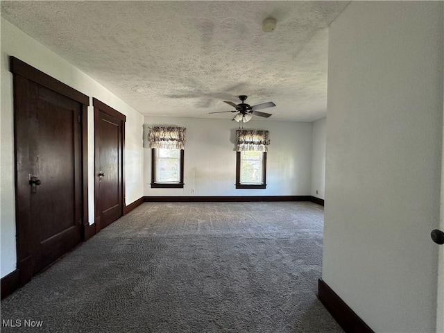 1905 Pine St SE, East Sparta, OH 44626 - interior space featuring a textured ceiling, dark colored carpet, baseboards, and ceiling fan