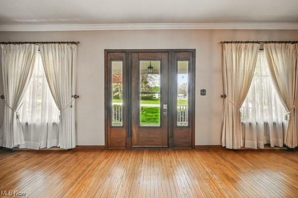 doorway featuring baseboards, crown molding, and wood finished floors