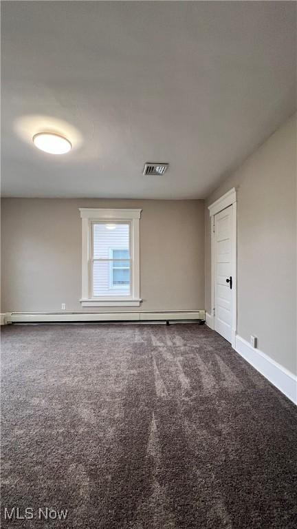 empty room with baseboards, dark colored carpet, and visible vents