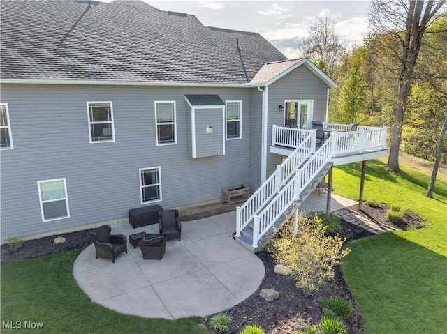 rear view of house featuring stairway, a deck, a patio area, and a lawn