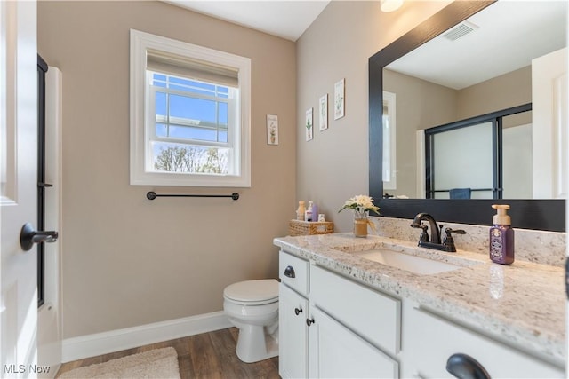 bathroom featuring baseboards, toilet, visible vents, vanity, and wood finished floors