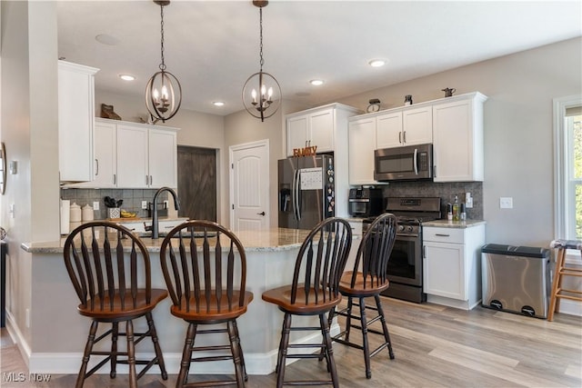 kitchen featuring a peninsula, stainless steel appliances, tasteful backsplash, and a chandelier