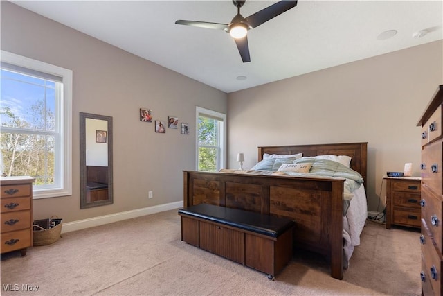 bedroom featuring light colored carpet, baseboards, and a ceiling fan