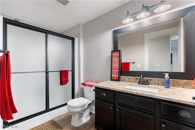 bathroom with a shower stall, vanity, visible vents, and wood finished floors